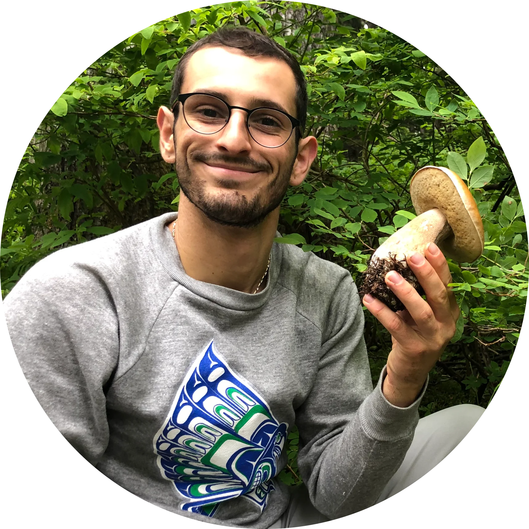 Antonio smiling in the forest, holding a large porcini mushroom